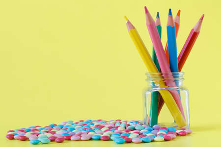 Colorful candies and jar on a yellow backgroundの写真素材