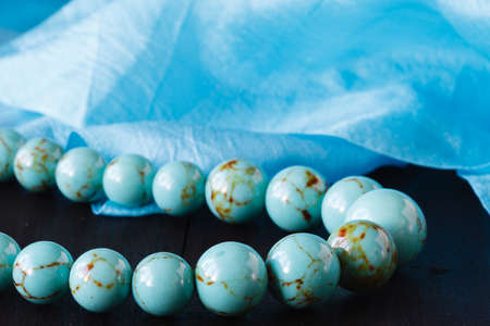 Turquoise bead on a wooden with silkの写真素材