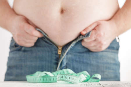 chubby man cannot button up his jean pant.Healthy and lose weight conceptの写真素材