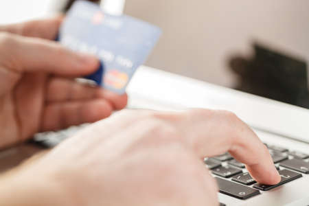 Close Up Of A Man Shopping Online Using Laptop With Credit Cardの写真素材