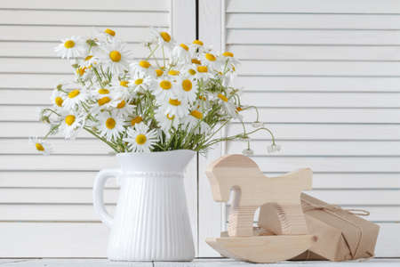 Bouquet of fresh daisies in white jug on wooden backgroundの写真素材