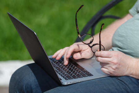 Male hands typing on laptop in the parkの写真素材