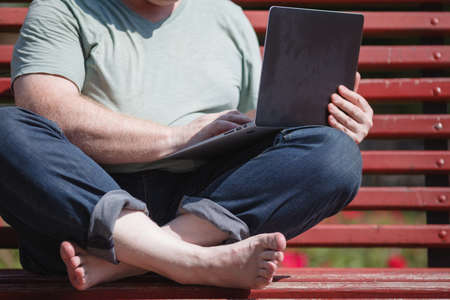 Male hands typing on laptop in the parkの写真素材