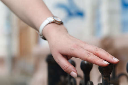 Girl standing at the iron fence and touches his handの写真素材