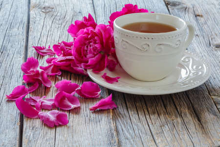 Hot tea and peony petals on dark wooden backgroundの写真素材