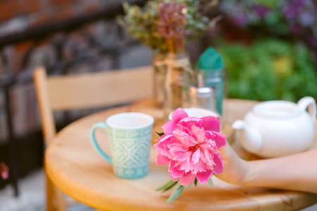 Woman sitting drinking tea at a cafe with flower in handの写真素材