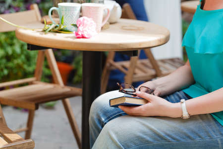 woman drinking coffee and reading book in an outdoor cafeの写真素材