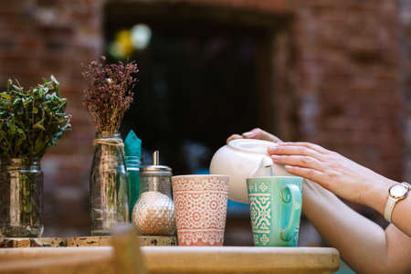 Person fills cup of tea in the cafeの写真素材