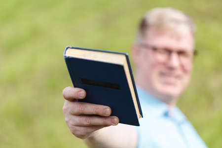 guy giving book to cameraの写真素材