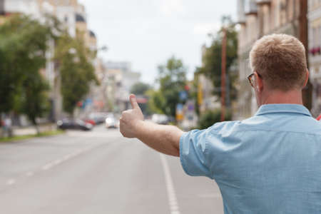man standing on the city street and hailing a taxiの写真素材