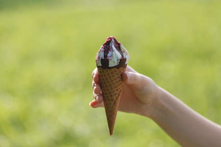 Ice cream in woman hand outdoors. Selective focus.