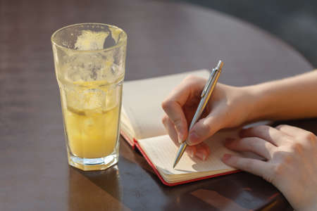 Young woman taking note. Writing with pen in notebook at the cafe