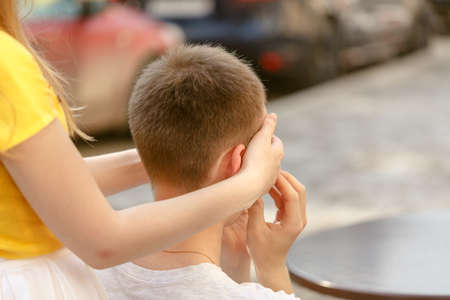 Guess who? Beautiful young woman covering eyes of her boyfriend and smiling while both standing outdoorsの写真素材