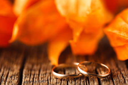 Wedding decoration. Red leaves on weathered table with wedding ringsの写真素材