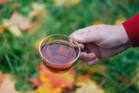 Man with cup of tea walk in autumn park with maple leavesの写真素材