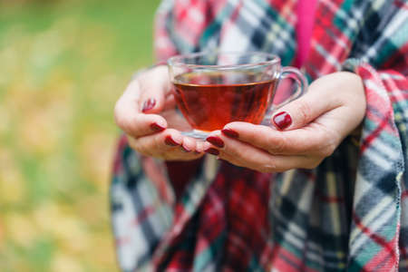 Female walking in cozy blanket in fall parkの写真素材