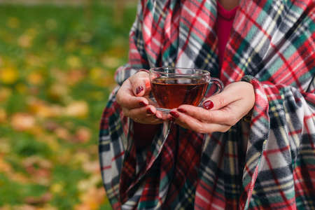 Female holds a tea in the autumn parkの写真素材
