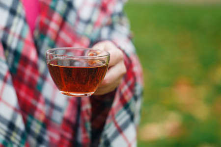 Female walking in cozy blanket in fall parkの写真素材