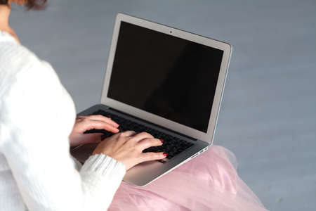 Top view on female hands writing on latop computer sitting on a wooden floor.の写真素材