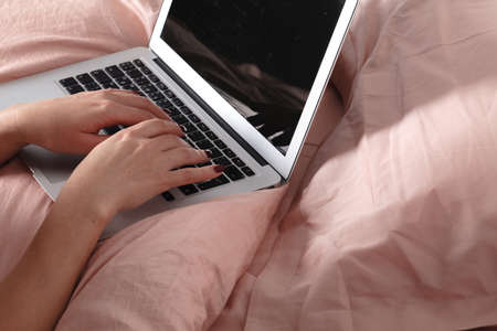 Bedroom evening - woman with laptop lying down in bedの写真素材