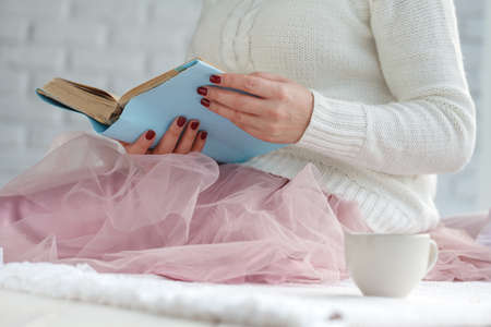young woman reading book and basking with plaid and coffee
