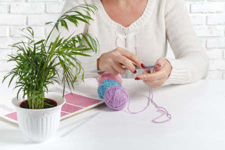 Women's hands are knitted. Process of knitting. Beautiful delicate wooden knitting with knitting...