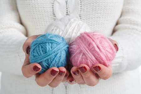 woman in a knitted sweater holding a  balls of yarn and knitting. concept of needleworkの写真素材