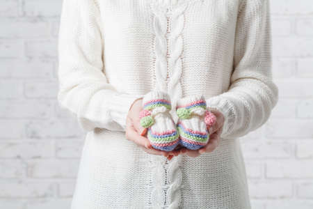 close up portrait of mother to be holding baby shoesの写真素材