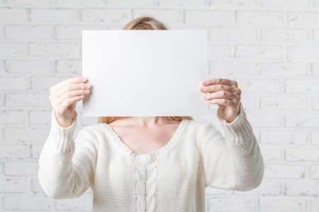 Young woman holding white banner with a place for your infoの写真素材