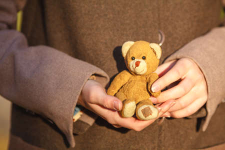 Woman holding toy bear in fall parkの写真素材