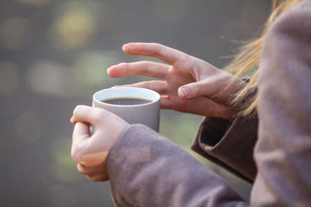 Close up of woman drinking from a cup against autumn leaves pattern