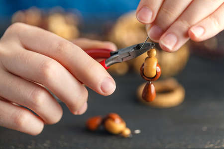 Pair of hands and pliers assembling a bead necklace.の写真素材