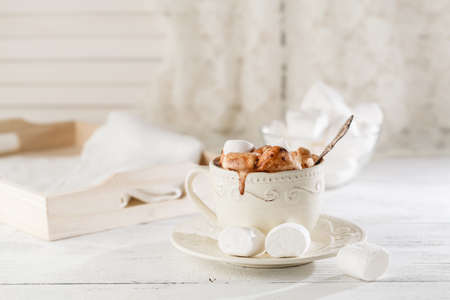 Mug of hot chocolate with marshmallows, on light wooden background