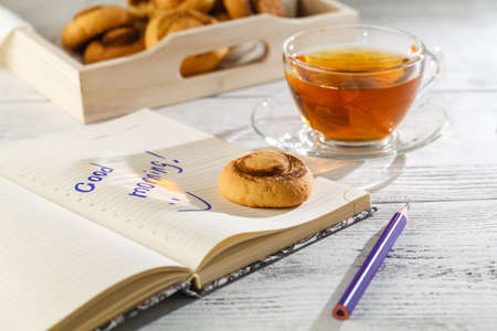 Time of Tea Break on the table top view. beautiful tablecloth with cup, spoon, notebook, cookies