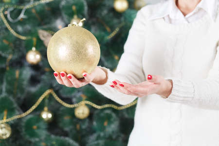 Beautiful girl hangs a Christmas toy on the Christmas tree. Happy Holidays!の写真素材