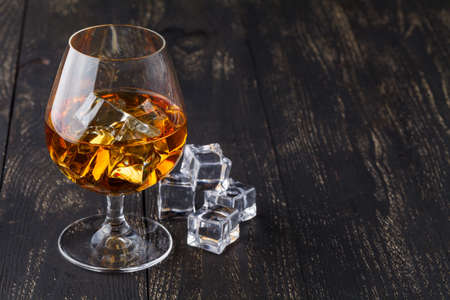 glass of whiskey with ice on a wooden backgroundの写真素材