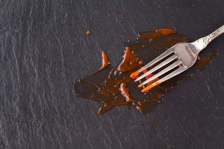 Fork stained with tomato ketchup on slate tableの写真素材