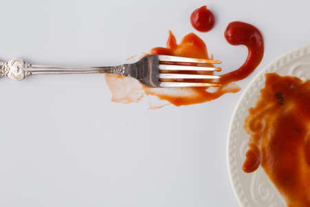 Fork stained tomato ketshup on table with dishの写真素材