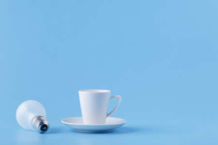 Energy for long day, coffee cup on blue with light bulbの写真素材