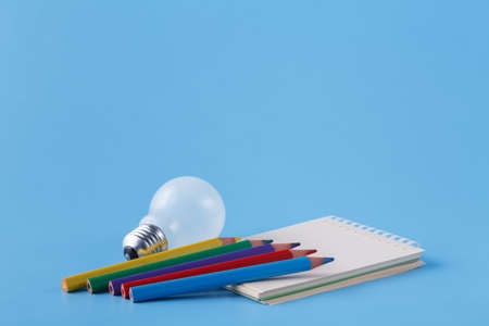 Pile of colour pencils on light blue background, creative idea concept
