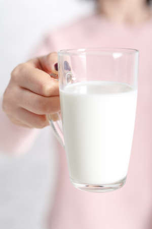 the woman is holding a glass mug of milkの写真素材