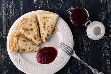 Freshly made crepes with honey on a beautiful plate and wooden backgroundの写真素材