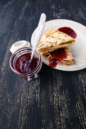 many thin pancakes with jam on the tableの写真素材