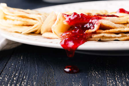 many thin pancakes with jam on the tableの写真素材