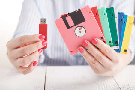 Female hold old floppy disk and modern flash driveの写真素材