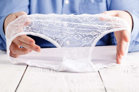 Man with lace female lingerie in hands, sex in roomの写真素材