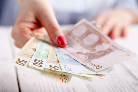 Female hands with banknotes give moneyの写真素材