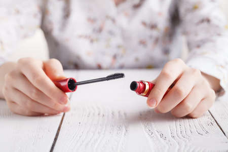 mascara in female hands on white tableの写真素材