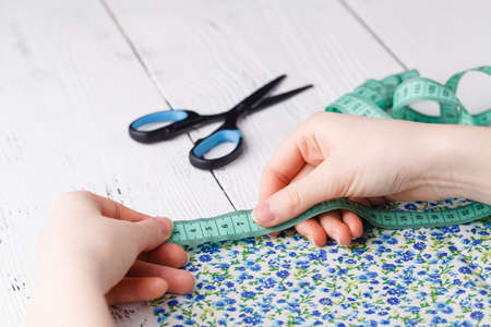 Cropped image of beautiful young designer working with sketches and measure tape in dressmaking salonの写真素材