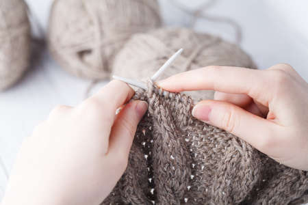 Knitting a wool scarf, closeup of the hands
